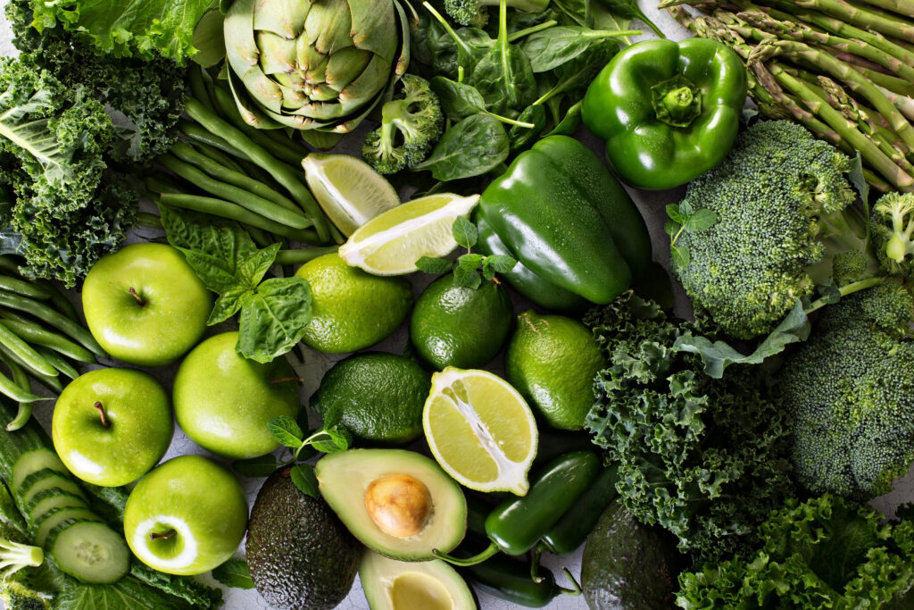 Variety of green vegetables and fruits spread on the table
