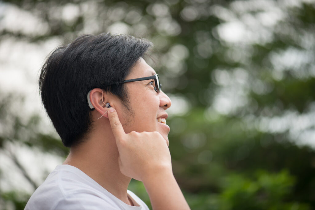 Man with hearing aid behind the ear outdoors.