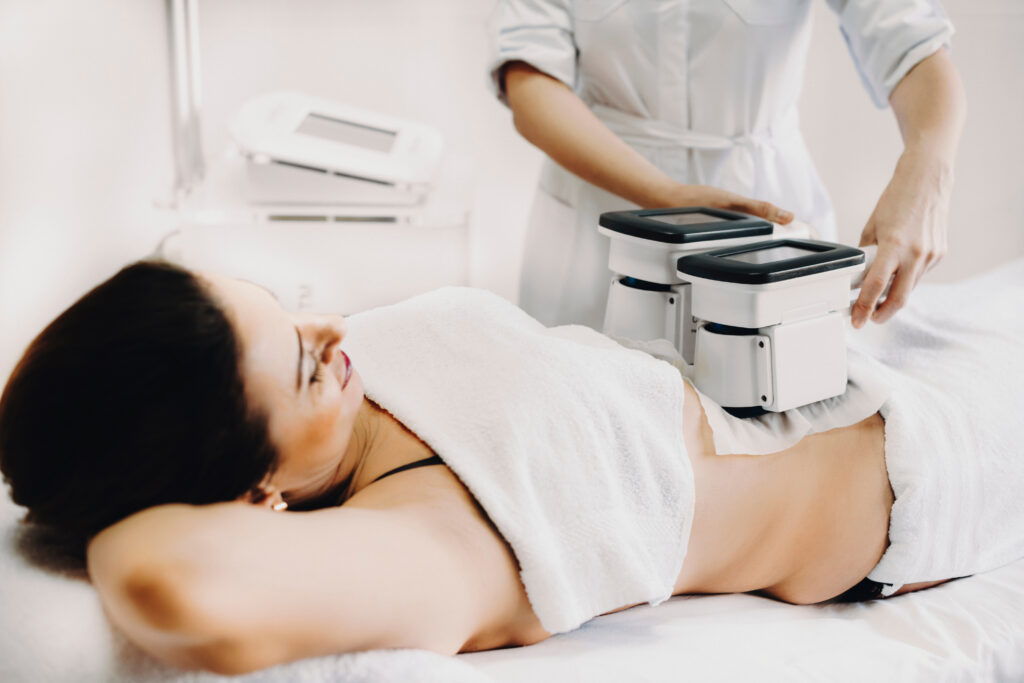 Adult woman doing cryolipolysis cool sculpting fat treatment procedure in a salon.