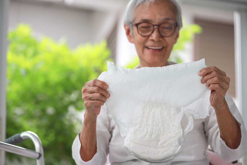 Smiling older woman showing disposable diaper for adult