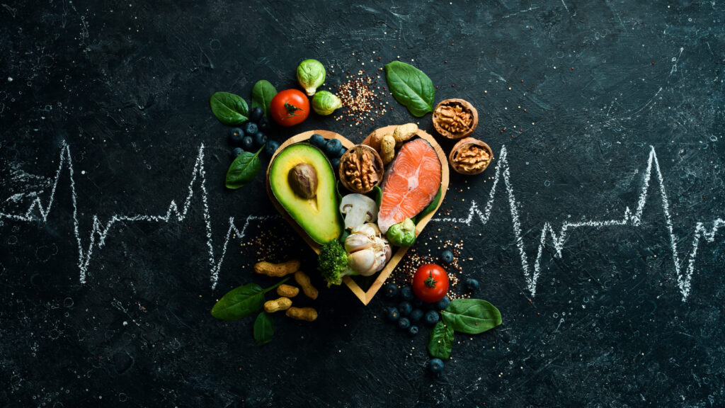 Healthy foods low in carbohydrates. Food for heart health: salmon, avocados, blueberries, broccoli, nuts and mushrooms. On a black stone background. 