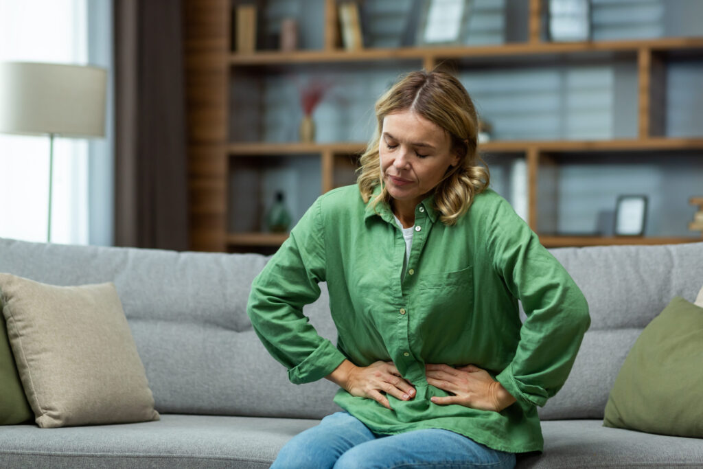 Woman sitting on couch experiencing pain due to chohns disease