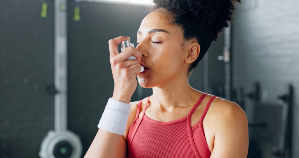Woman using asthma inhaler at the gym