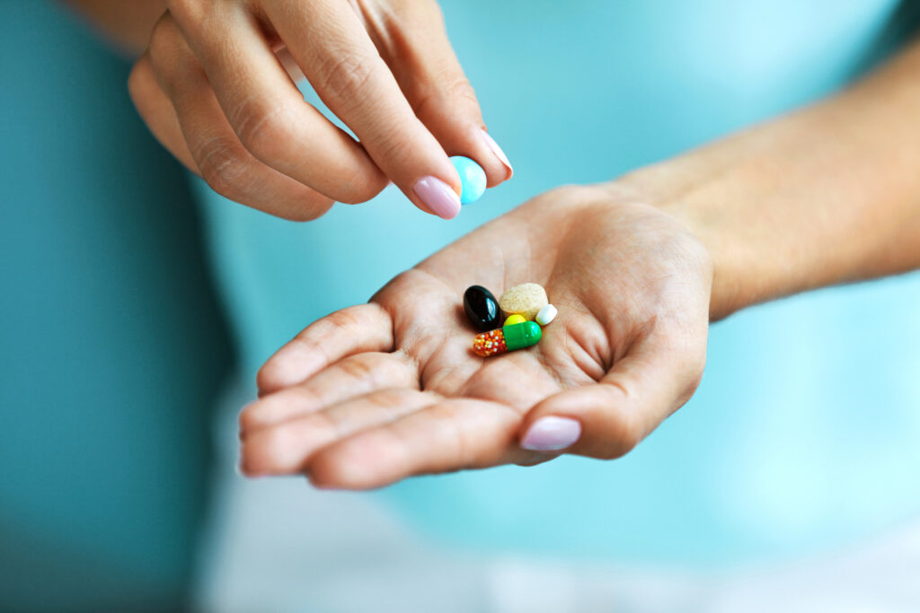Vitamins And Supplements. Closeup Of Female Hand Holding Variety Of Colorful Pills On Palm. Close-up Of Woman Fingers Taking Medication Tablets, Capsules From Hand. Medicine Concept. High Resolution