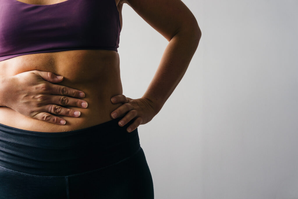 Woman wearing activewear holding her stomach in pain