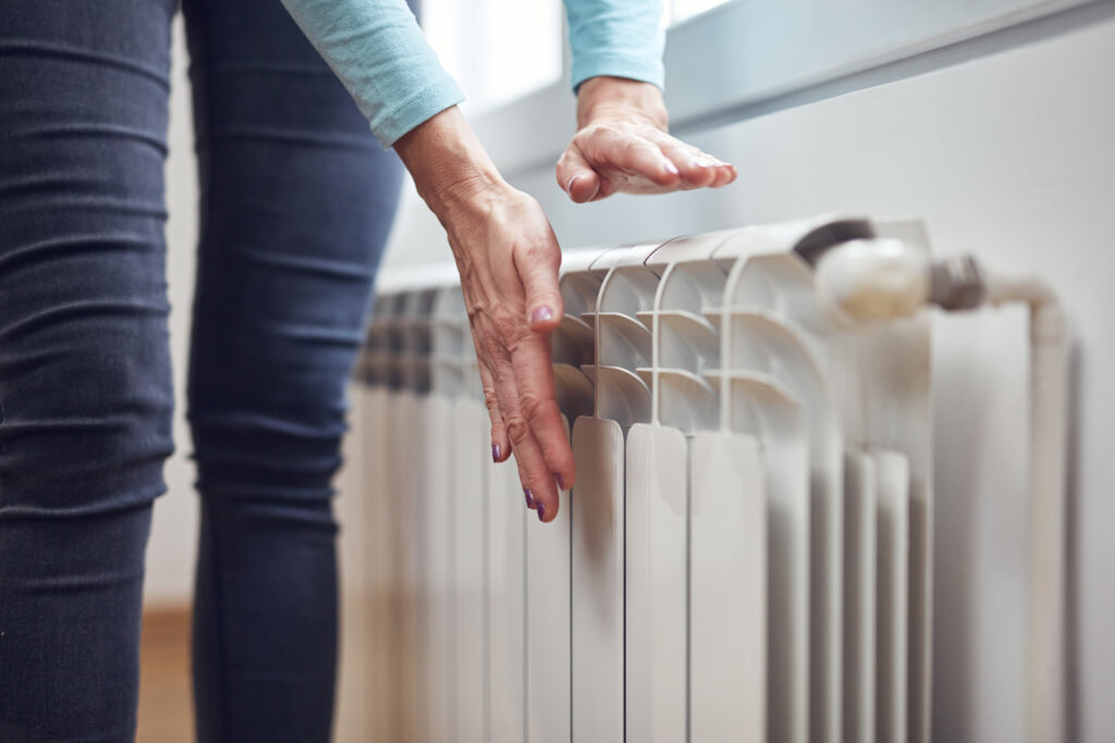 Woman heating her hands on the radiator.