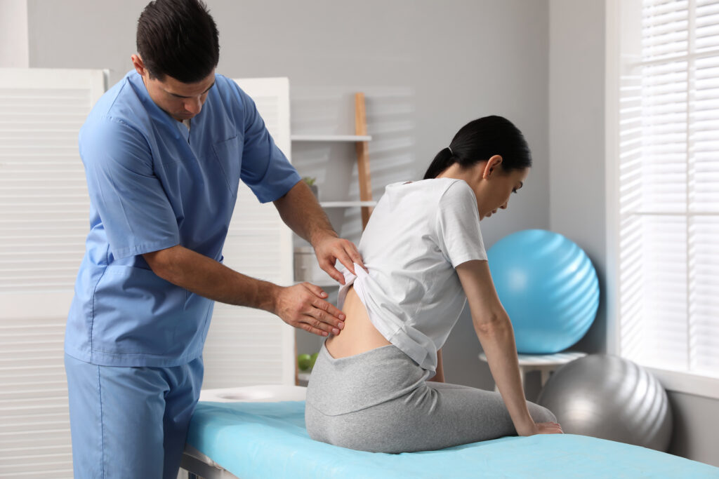 Male doctor examining the spine of a female patient.