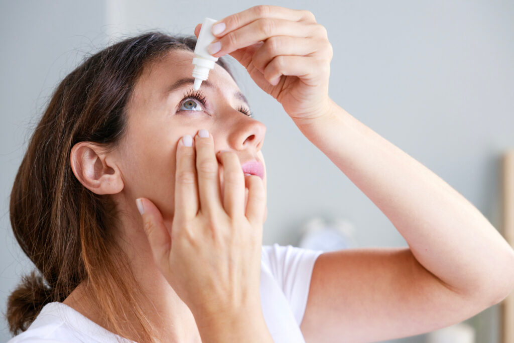Young woman putting eye drops at home.